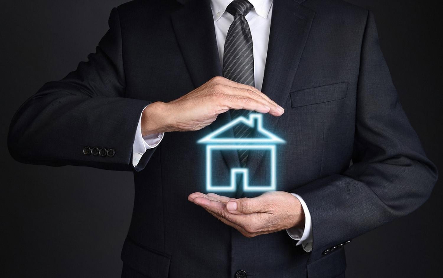 Businessman gesturing protectively around a glowing house icon, symbolising villa security in Dubai