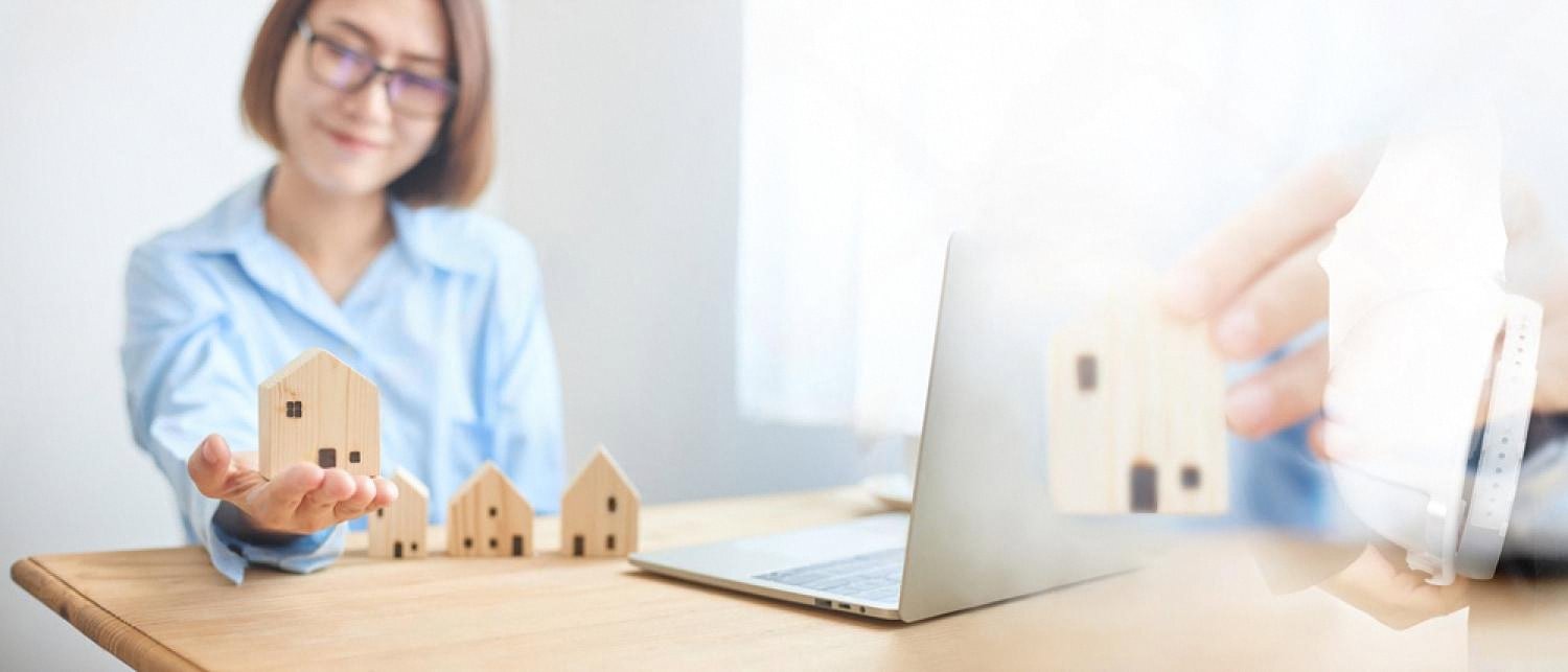 Consultant reviewing villa security options on a laptop with model houses on the desk